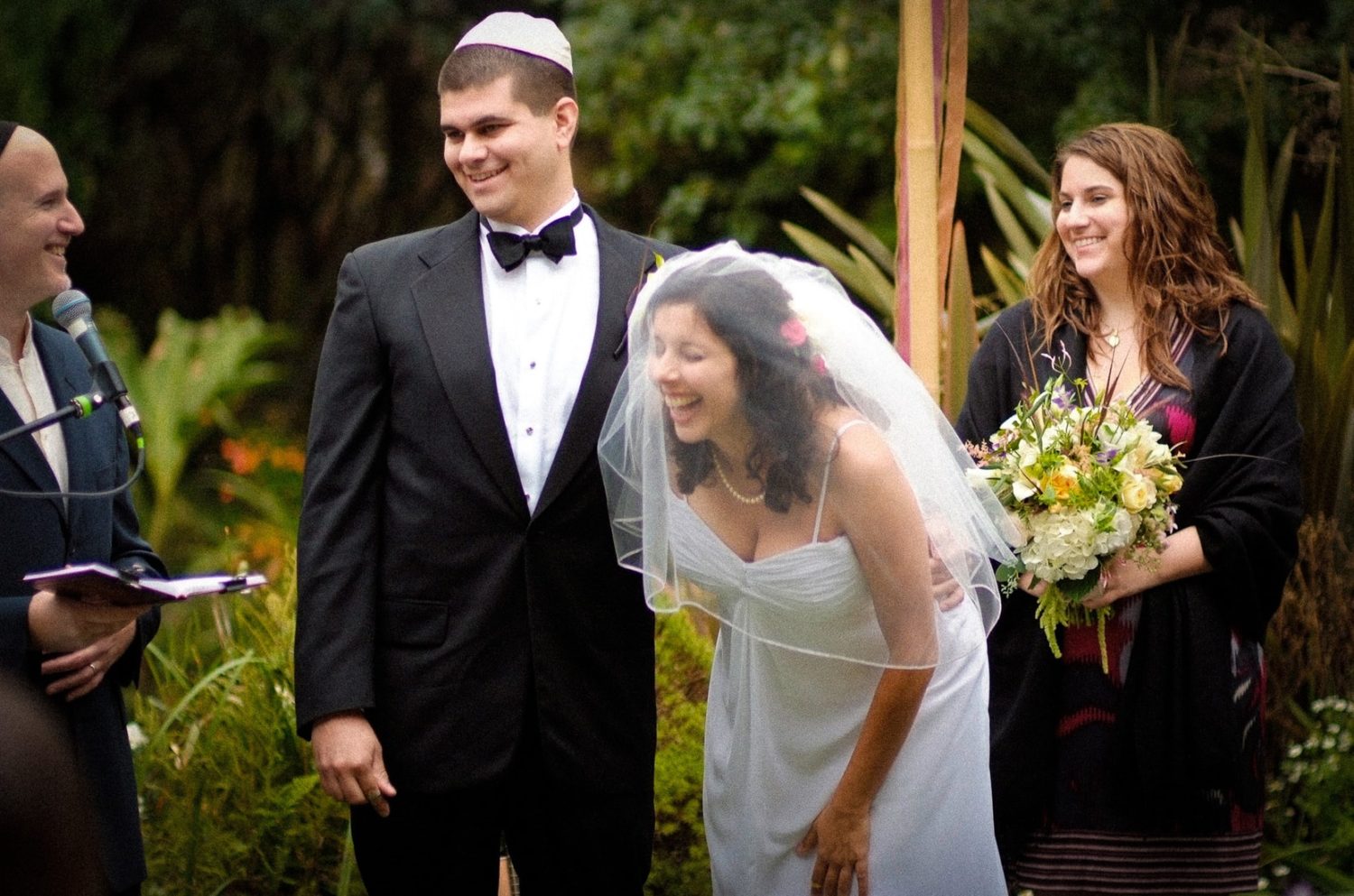 A groom wearing a suit and tie standing next to his bride wearing her wedding dress and veil under the chuppah at their Jewish Wedding